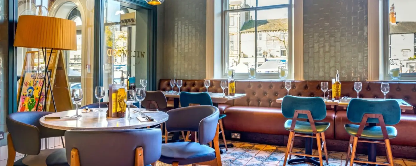 Main restaurant web banner for Wildwood Taunton, showcasing table layouts and stylish indoor booth seating for lunch or dinner.