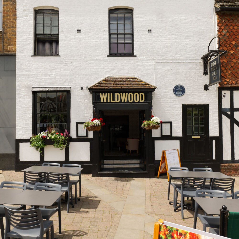 Outdoor patio seating area at Wildwood Italian restaurant on High Street in Crawley, showcasing the historic building front.